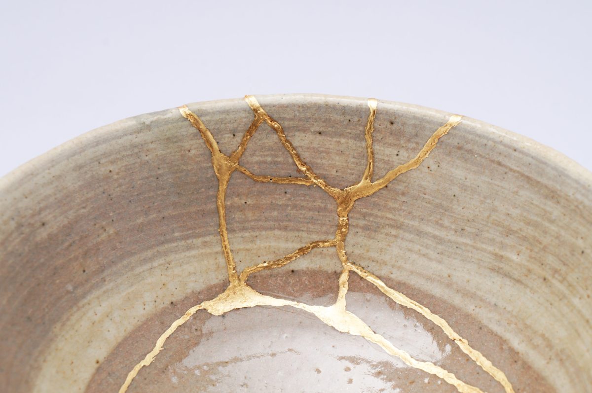 Kintsugi beige bowl. Gold cracks restoration on old Japanese pottery restored with the antique Kintsugi restoration technique. The beauty of imperfections. japanese pottery repair gold. japanese art of repairing cracks with gold. japanese art of fixing broken pottery